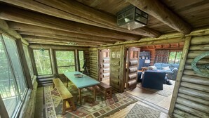 L’intérieur d’une cabane en rondins, avec une table en bois, des bancs et un tapis à motifs.