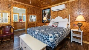 A wooden-paneled room with a bed, a desk, a chair, and a ceiling fan. - Historic Rockaway Beach Cottage 8 (Rockaway Beach)