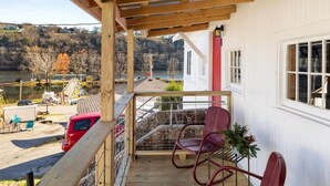 A wooden deck with a view of a river and houses, a red car, and a red chair. - Historic Rockaway Beach Cottage 8 (Rockaway Beach)