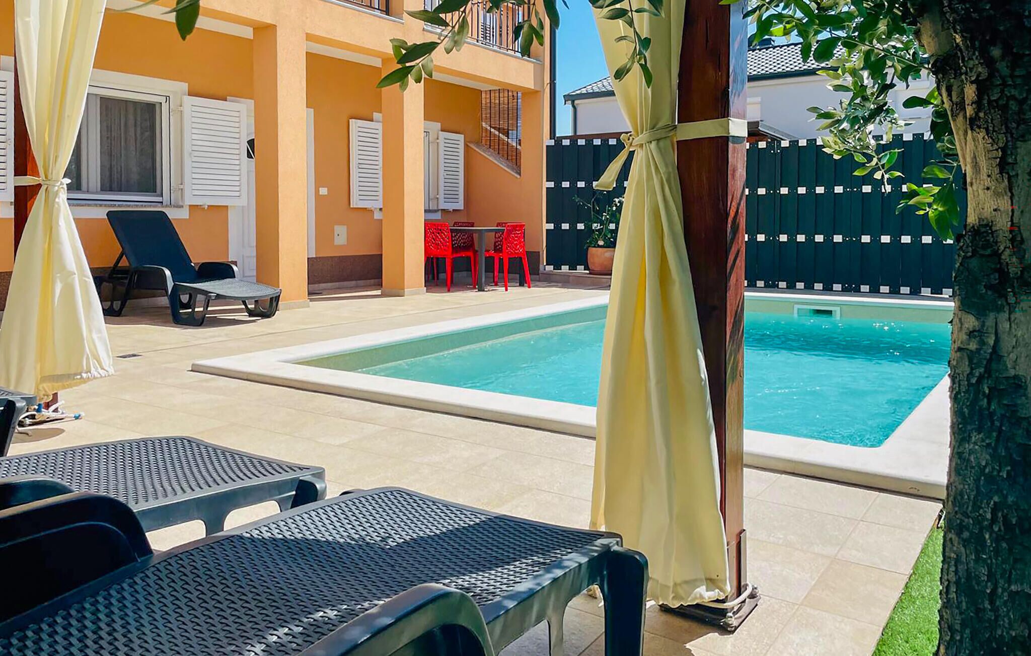 A pool area with lounge chairs, a table, and a small pool.