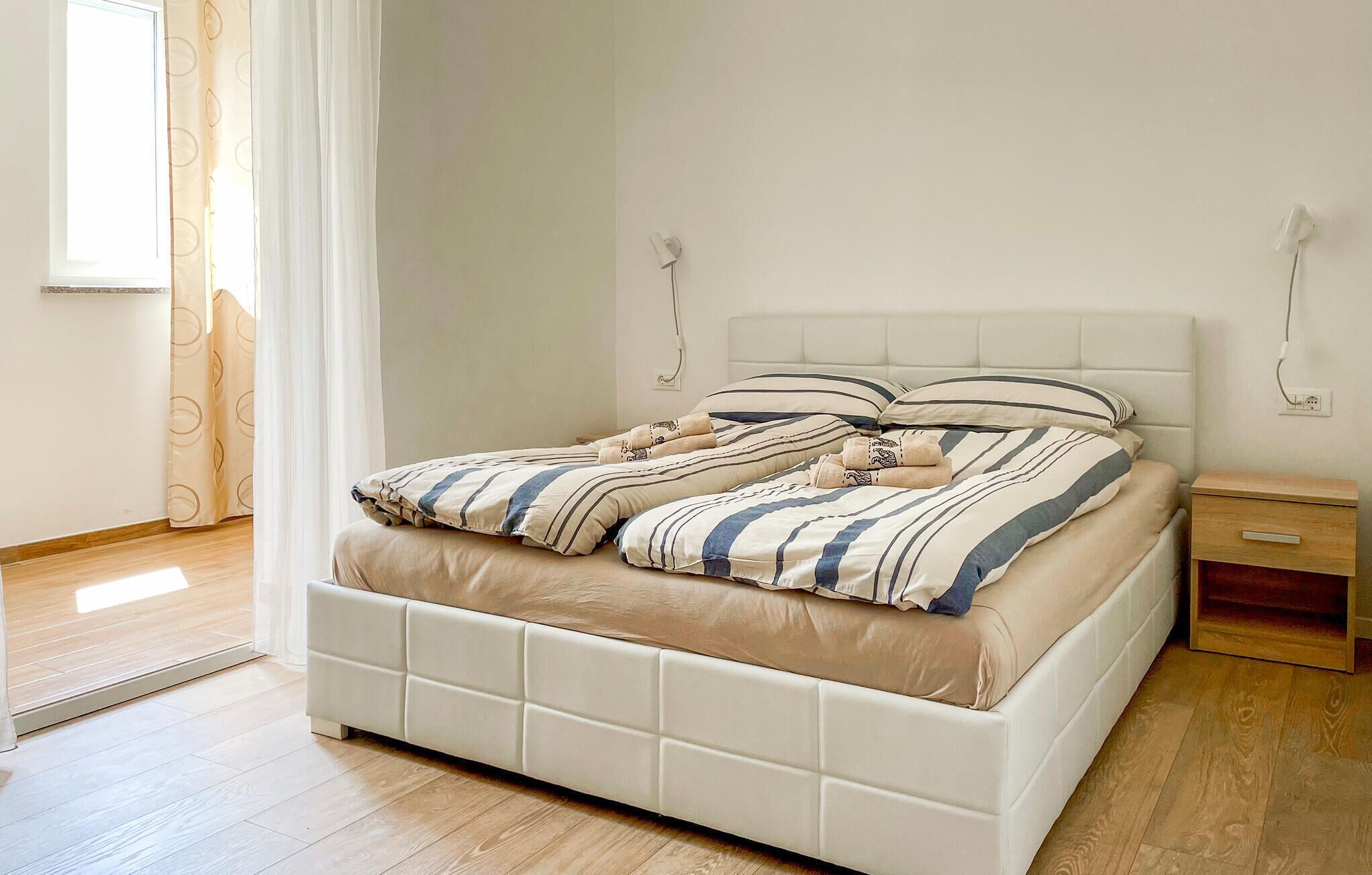 Ein Schlafzimmer mit einem Bett, Nachttischen und einem Fenster.