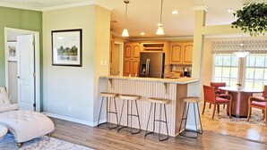 Une cuisine moderne avec des meubles en bois, un îlot central doté de tabourets et un éclairage suspendu.