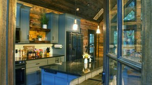 A modern kitchen with blue cabinets, a black countertop, and a built-in refrigerator.