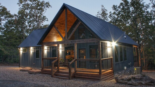 A wooden cabin with a large porch and a steeply pitched roof.