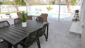 Eine Terrass mit Pool, überdachter Sitzgruppe und Tisch mit Stühlen.