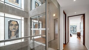 Ein modernes Interieur mit Glasgeländer, einer Treppe und Kunstwerken an den Wänden.