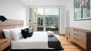 Ein modernes Schlafzimmer mit Bett, Nachttischen, einem Schminktisch und einem großen Fenster mit Blick.
