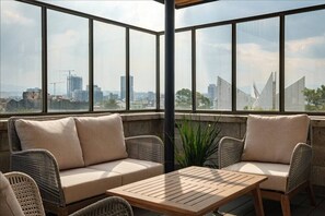 A corner seating area with a view of a cityscape through large windows.