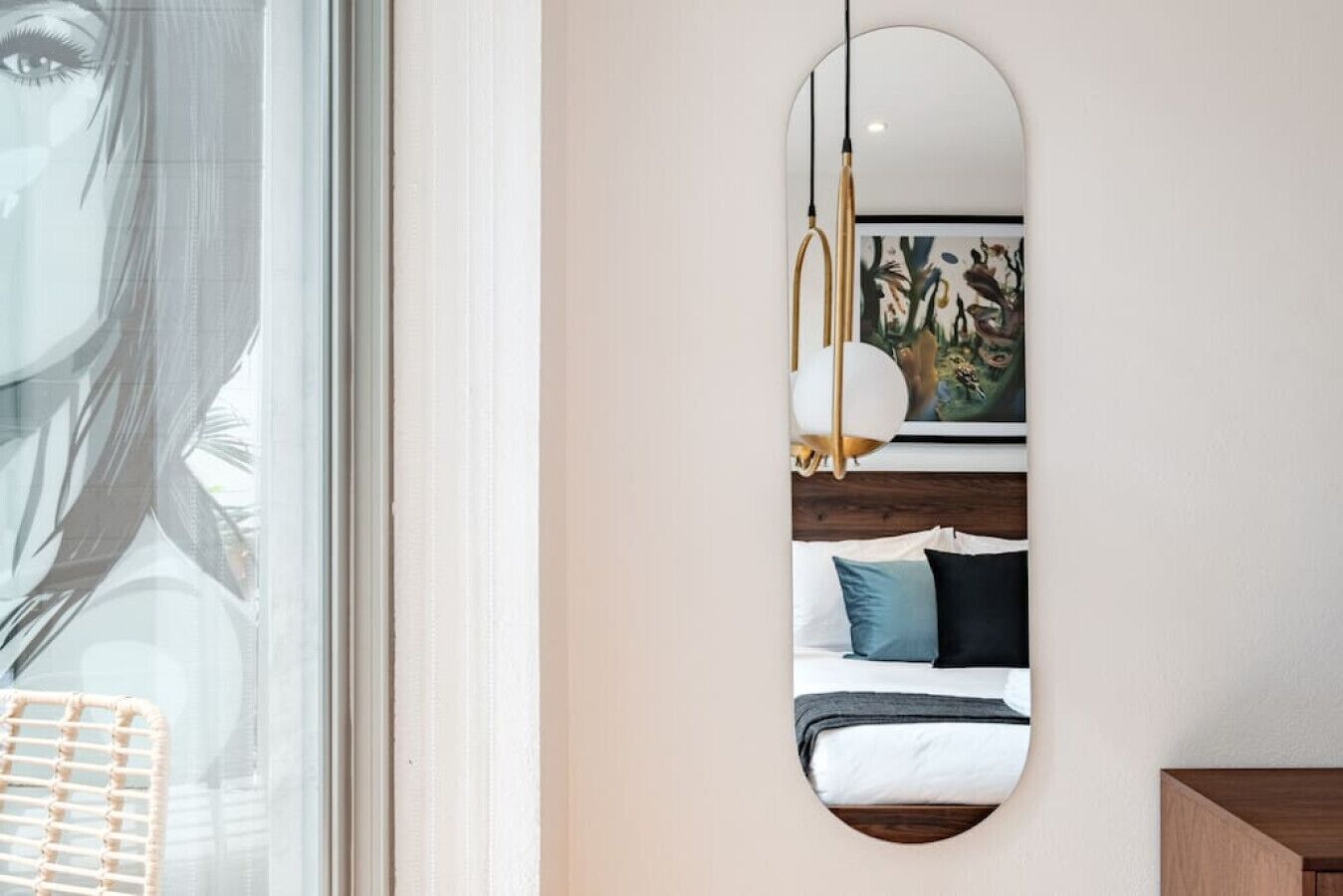 A bedroom with a bed, pillows, a hanging light fixture, and a large window.