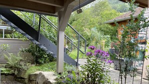 Ein überdachter Außenbereich mit Treppe, Steinmauern und verschiedenen Pflanzen.