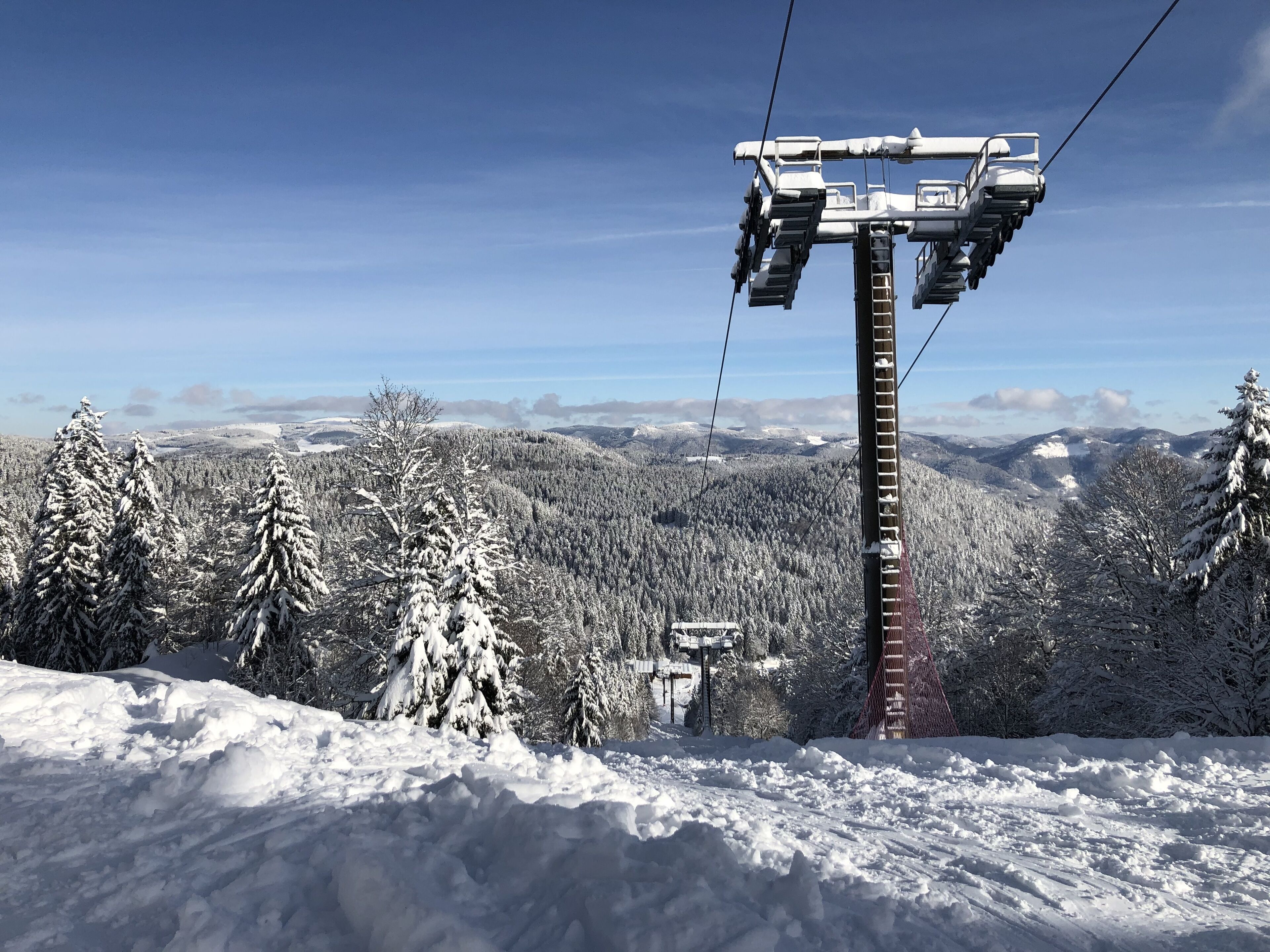A snow-covered mountain landscape with a ski lift and a chairlift.