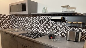 Eine moderne Küche mit integriertem Mikrowellenherd, Edelstahlgeräten, einer gemusterten Spritzschutzwand und einer Arbeitsplatte mit Glasbehältern und einem Toaster.