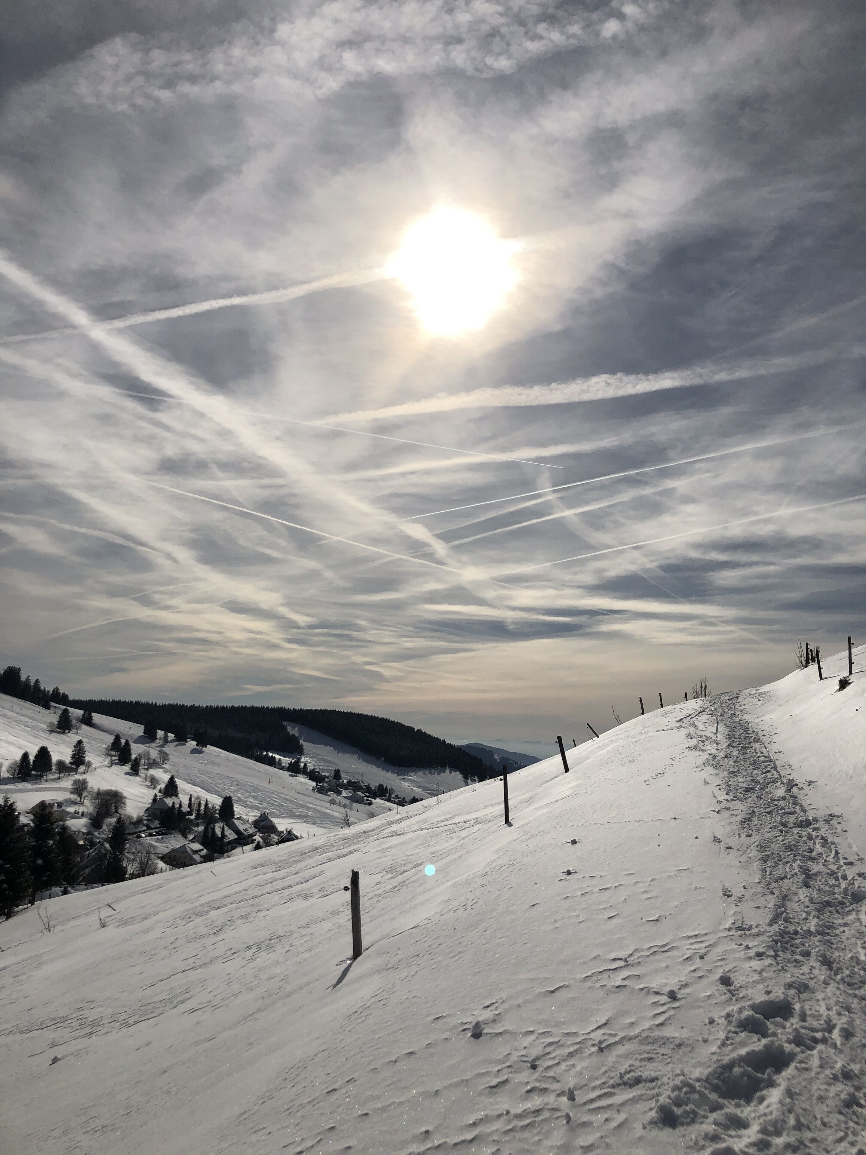 A snow-covered landscape with a clear sky and the sun shining.