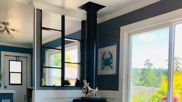 A living room with a fireplace, two armchairs, a coffee table, and a view of a garden. - Beautiful Oceanview Retreat 2 Bedroom Home (Port Hadlock-Irondale)