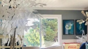 A modern living room with a large window, a sofa, a coffee table, and a decorative plant. - Beautiful Oceanview Retreat 2 Bedroom Home (Port Hadlock-Irondale)
