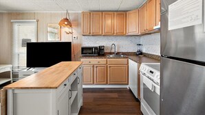 Une cuisine moderne avec des meubles en bois, des appareils en acier inoxydable et un plan de travail en bois.