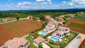 A residential area with houses, a swimming pool, and agricultural fields.