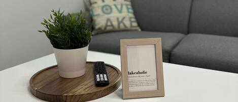 A white table with a potted plant, a framed dictionary, and a remote control.