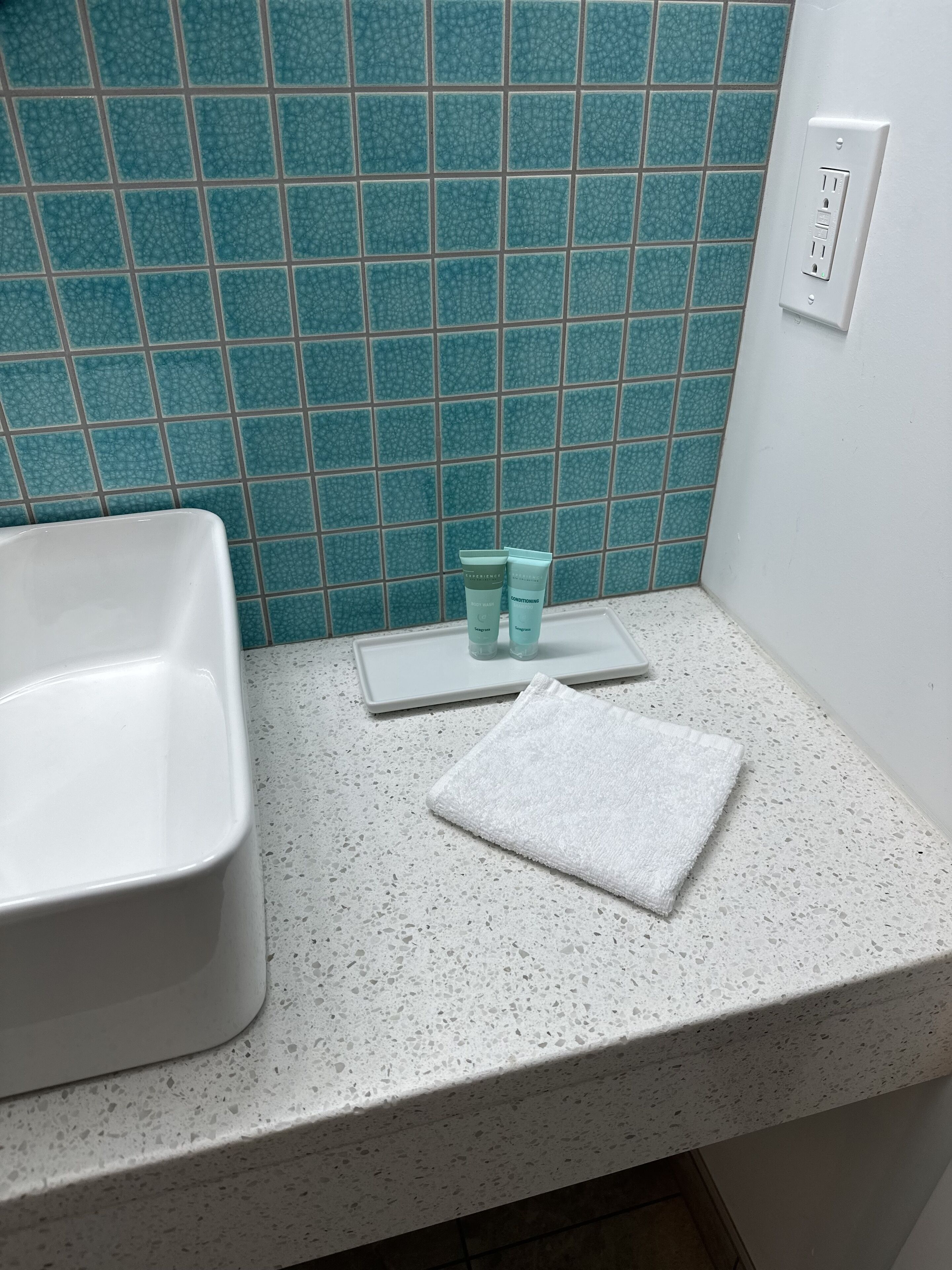 Un baño con lavamanos y encimera blancos, y pared de azulejos azules.