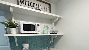 A modern kitchen with a white countertop, a built-in microwave, a coffee maker, and a sink.