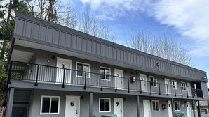 A multi-story motel with numbered rooms, outdoor seating, and a balcony.