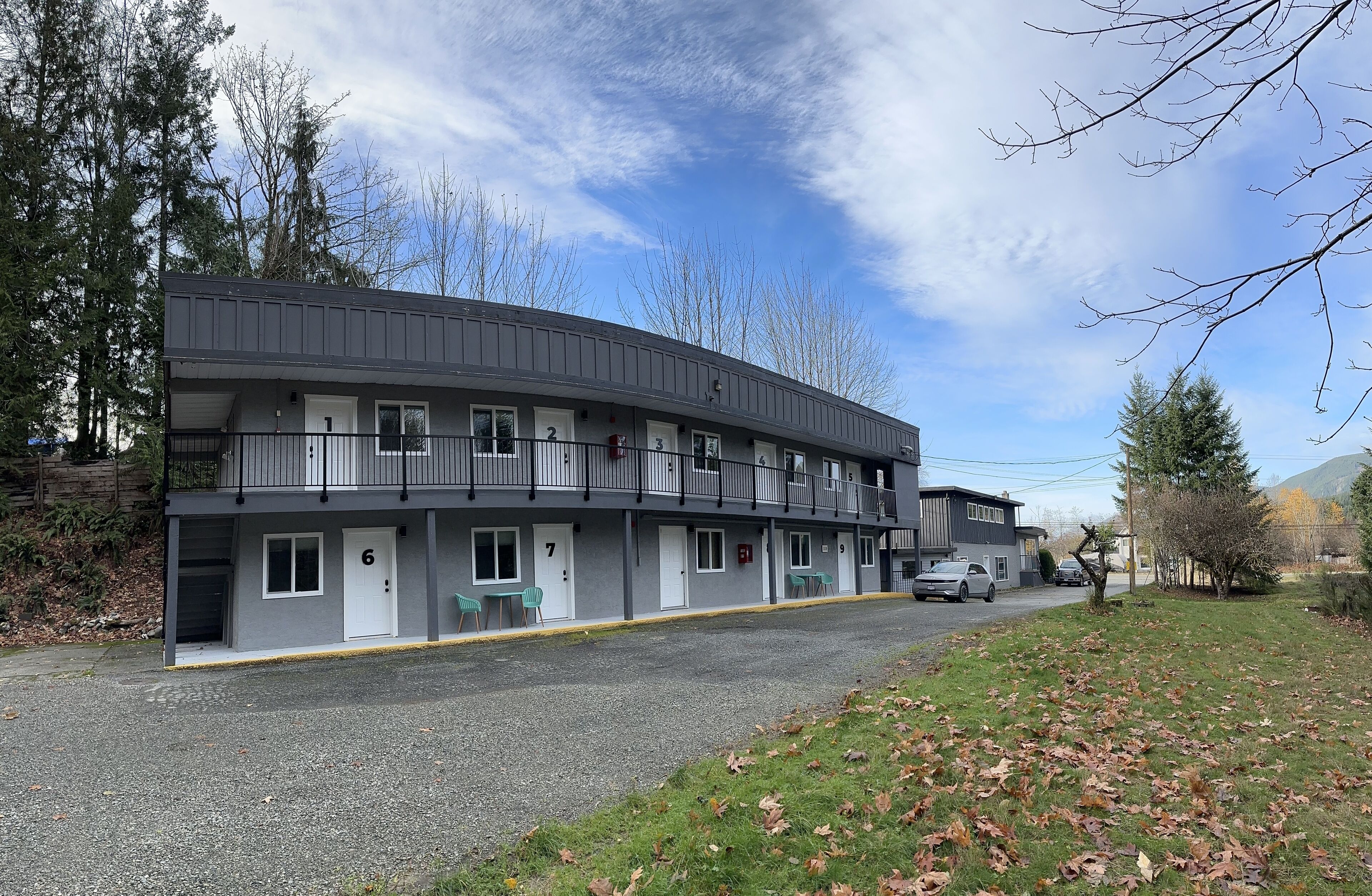 A multi-story motel with a grey exterior, numbered rooms, and a parking area.