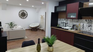 A modern kitchen with a wooden countertop, a wine bottle, and a potted plant. - Le Bag 3 chambres appartement familial (Colmar)