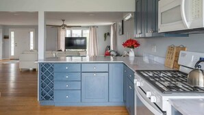 Una cocina moderna con armarios azules, una estufa a gas, un microondas y una isla grande con un fregadero.