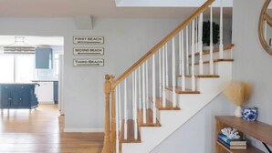 Una escalera con barandillas de madera y pasamanos blancos, que conduce a una plataforma con un letrero que indica tres niveles de playa.