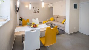 A modern living room with a sofa, a dining table with chairs, and a fruit bowl. - 2 bedroom beautiful home in Porec (Porec)