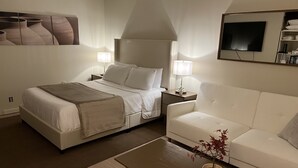A hotel room with a bed, a white sofa, a coffee table, a lamp, and a TV. - Comfortable Condo in Park City (Park City)