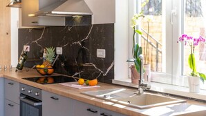 Een moderne keuken met een marmeren achterwand, een inbouwoven en een raam met uitzicht op de omgeving.