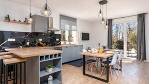 Een moderne keuken met een centraal eiland, grijze kastjes en hanglampen.