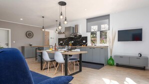 Een moderne keuken met een eethoek, een tv aan de muur en een groot raam voor natuurlijk licht.