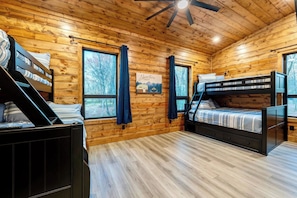 A cabin-style room with wooden walls, a bunk bed, and a window with curtains. - All is Found Riverfront Cabin with Sauna (Broken Bow)