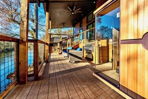 Een houten terras met een barbecue en zithoek, met uitzicht op een waterpartij.