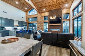 A modern interior with a kitchen, dining area, and seating with large windows.