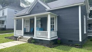 Ein zweistöckiges Haus mit Veranda und überdachter Eingangspforte.