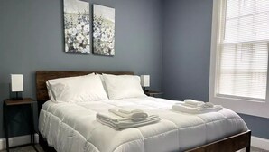 Ein Schlafzimmer mit einem Bett, zwei Nachttischen und einem Kunstwerk an der Wand.