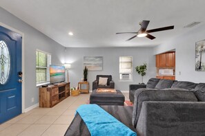 A living room with a television, sofa, and a ceiling fan.