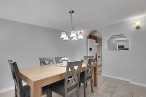 A dining area with a wooden table, six chairs, and a chandelier.