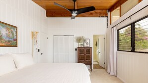 A bedroom with a bed, a ceiling fan, a wooden ceiling, a window with curtains, and a door.
