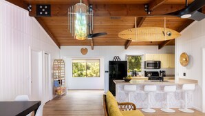 A modern kitchen with white cabinetry, a central island with bar stools, and a dining area with a wooden table and white chairs.