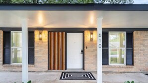 Una casa moderna amb una porta d'entrada, dues finestres amb persianes i el número 610 a la paret.