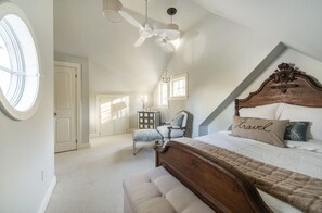 Une chambre à coucher avec un grand lit, une chaise, un bureau et un ventilateur de plafond.