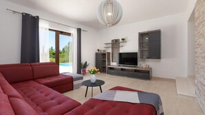 Ein modernes Wohnzimmer mit einem roten Sofa, einem Fernseher und einem kleinen Tisch mit Blumen.