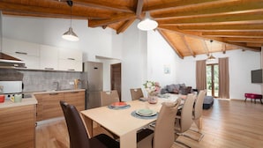 Eine moderne Küche mit weißen Schränken, einem Edelstahlkühlschrank und einem Essbereich mit Holztisch und Stühlen.
