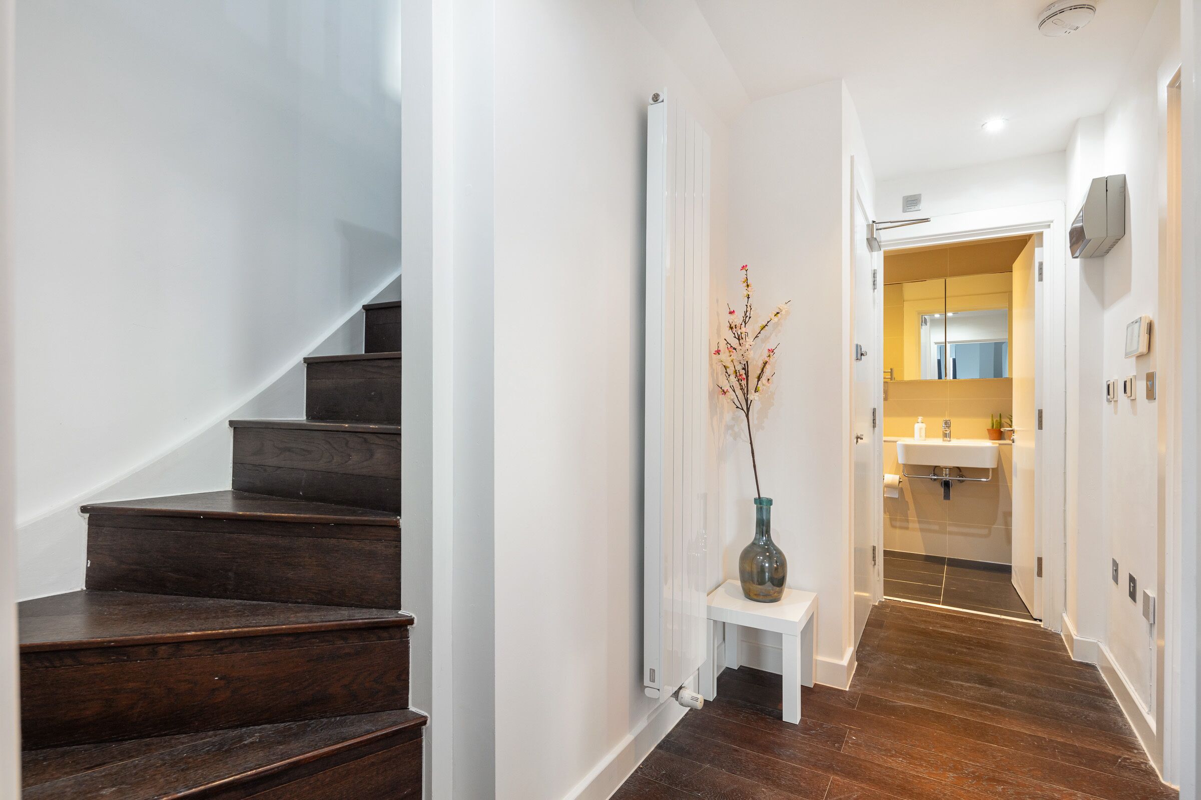 A staircase leading to a bathroom with a white sink and a mirror.