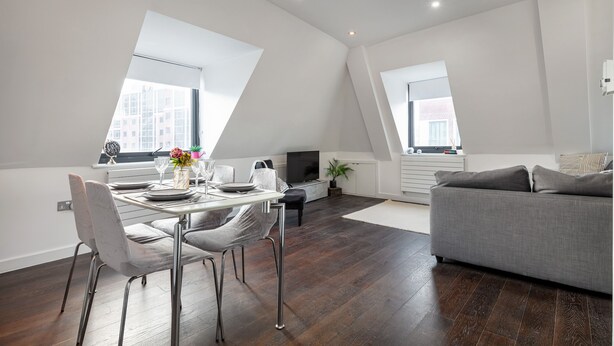 A modern loft apartment with a dining area, a sofa, and a TV. - Farringdon/St Pancras penthouse (London)