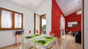 A dining area with a table set for four, a microwave, and a red accent wall. - Stunning home in Kastelir-Labinci (Kastelir-Labinci)